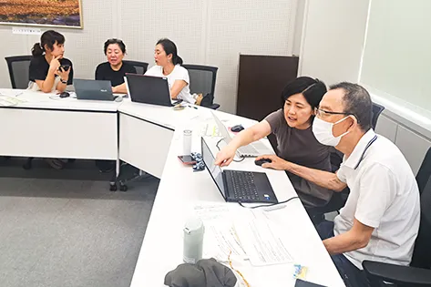 ノートパソコンで翻訳作業をしている職員